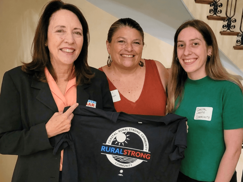 Teresa and partners holding a Rural Strong Community t-shirt